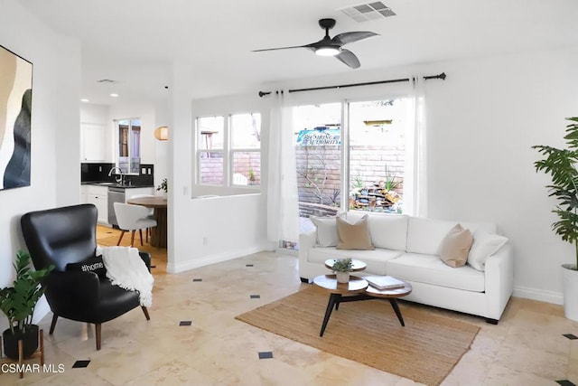 tiled living room with ceiling fan and sink