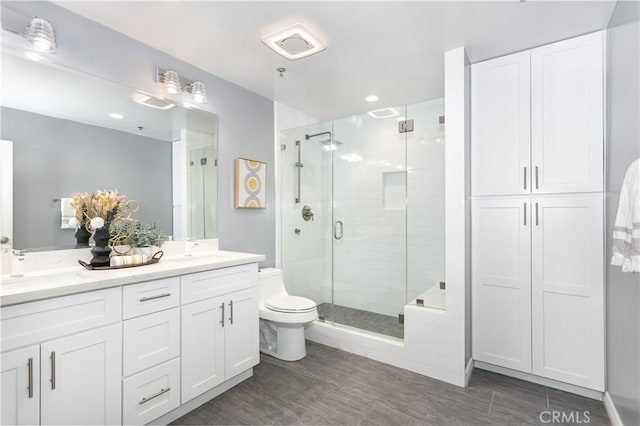 bathroom with toilet, a shower with shower door, and vanity