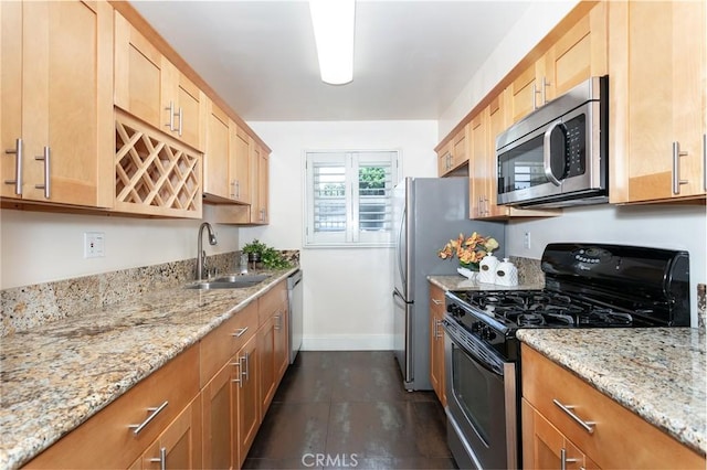 kitchen with dark tile patterned floors, appliances with stainless steel finishes, sink, and light stone counters