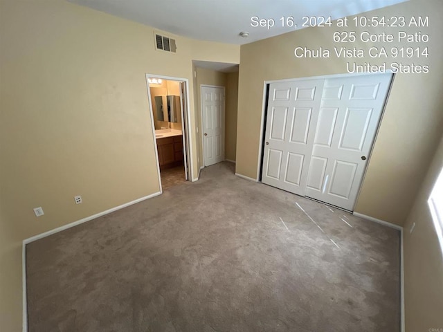 unfurnished bedroom featuring ensuite bath, a closet, and carpet flooring