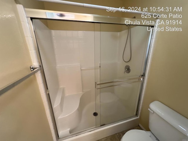 bathroom featuring a shower with shower door and toilet