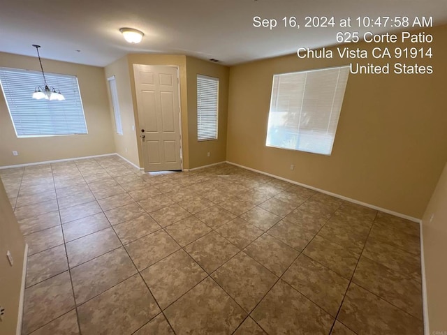 spare room featuring an inviting chandelier and tile patterned floors