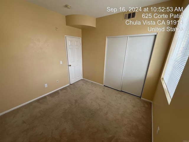 unfurnished bedroom with light carpet and a closet