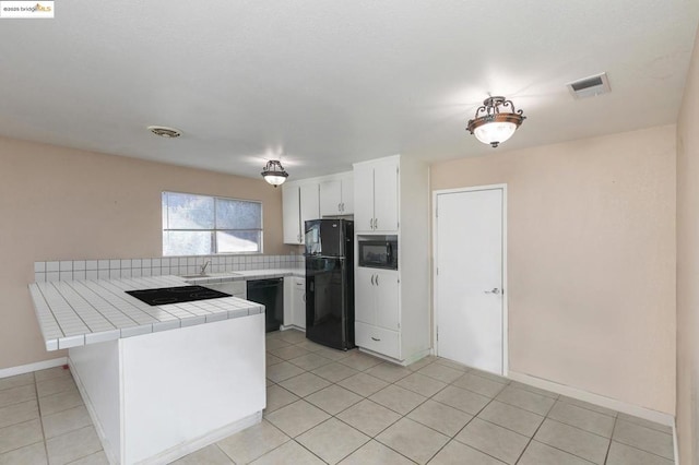 kitchen featuring light tile patterned floors, white cabinetry, tile countertops, kitchen peninsula, and black appliances