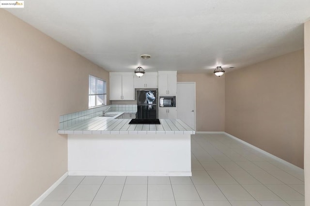 kitchen featuring kitchen peninsula, tile counters, white cabinets, and black appliances