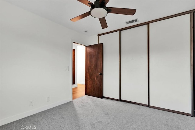 unfurnished bedroom with light colored carpet, a closet, and ceiling fan