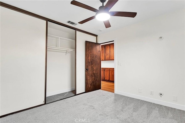 unfurnished bedroom featuring light carpet, a closet, and ceiling fan