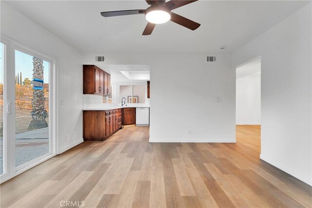 unfurnished living room featuring sink, light hardwood / wood-style flooring, and ceiling fan