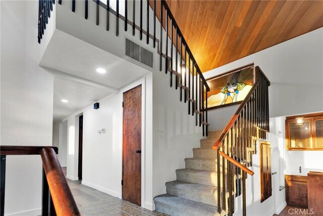 stairway with wooden ceiling and a towering ceiling