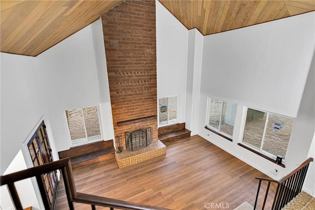 living room with hardwood / wood-style floors, wood ceiling, a brick fireplace, and high vaulted ceiling