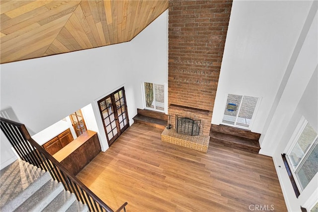 unfurnished living room with wood ceiling, a brick fireplace, high vaulted ceiling, and wood-type flooring