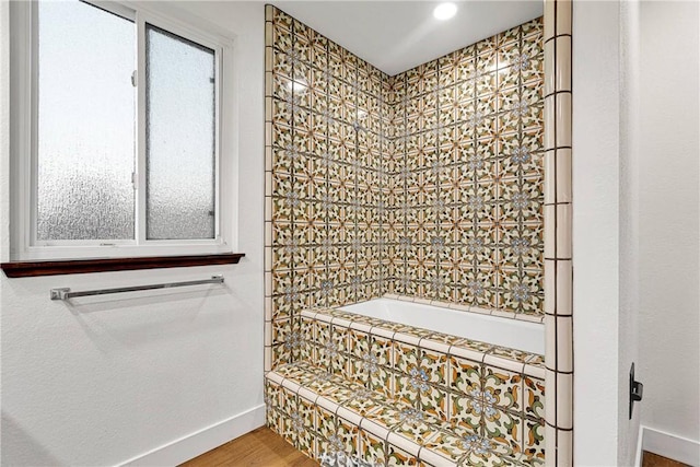 bathroom with wood-type flooring and tiled bath