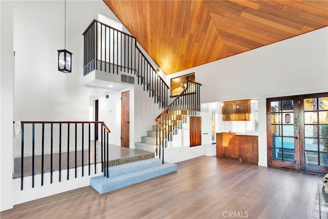 staircase featuring hardwood / wood-style flooring, high vaulted ceiling, french doors, and wooden ceiling