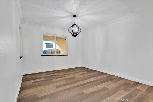 spare room with crown molding, wood-type flooring, a notable chandelier, and a textured ceiling