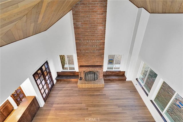 unfurnished living room with dark hardwood / wood-style flooring, a brick fireplace, wood ceiling, and high vaulted ceiling