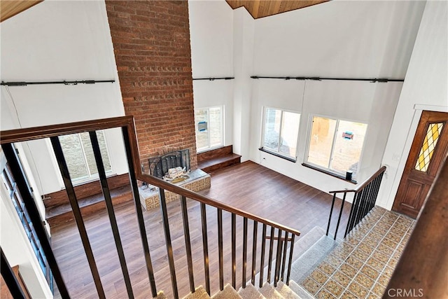 stairs featuring hardwood / wood-style floors, a towering ceiling, and a fireplace