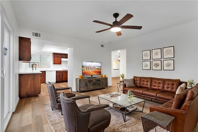 living room with sink, ceiling fan, and light hardwood / wood-style flooring