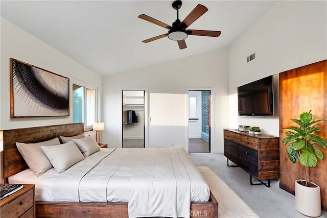 bedroom with ceiling fan, light colored carpet, vaulted ceiling, and ensuite bath