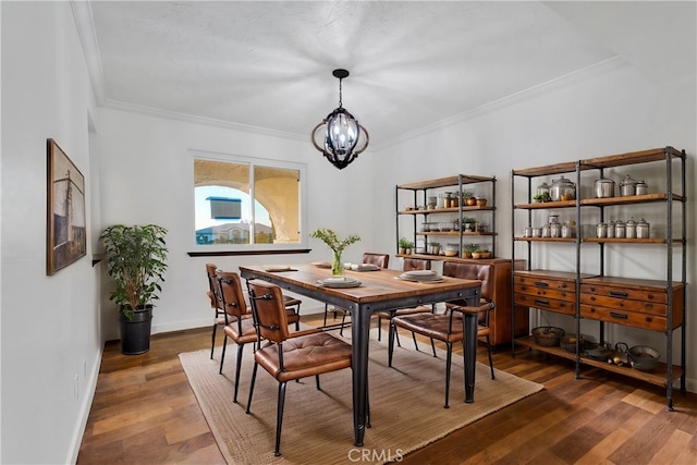 dining space featuring an inviting chandelier, ornamental molding, and dark hardwood / wood-style flooring