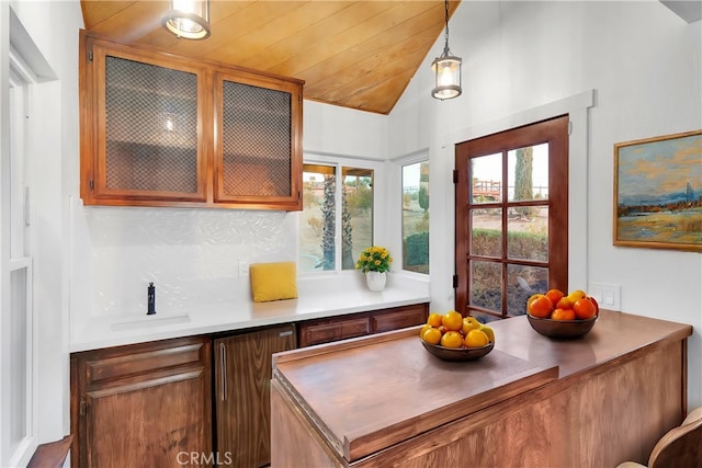 kitchen with vaulted ceiling, pendant lighting, backsplash, wooden ceiling, and sink