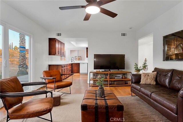 living room featuring ceiling fan, sink, and light hardwood / wood-style flooring