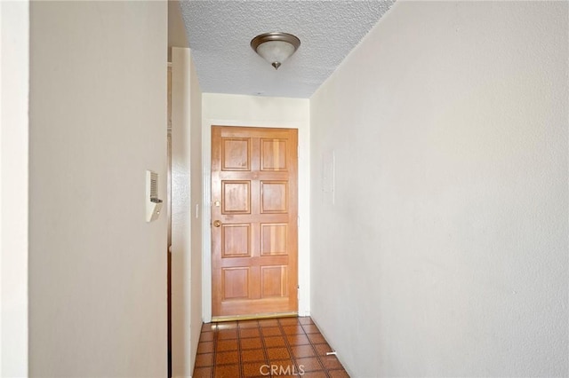 hall featuring a textured ceiling and dark tile patterned floors