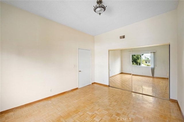 unfurnished bedroom featuring light parquet flooring and a closet