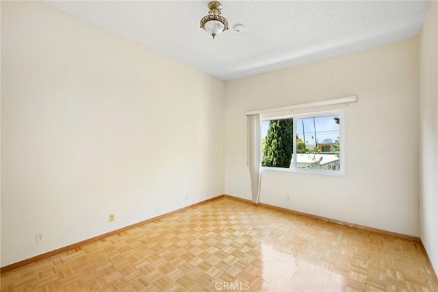 spare room featuring light parquet flooring and a textured ceiling