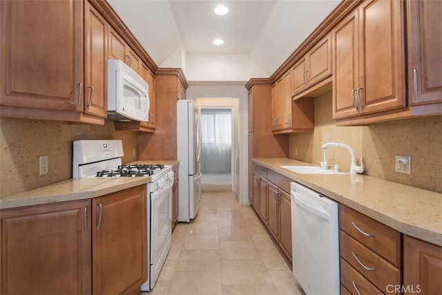 kitchen with tasteful backsplash, light stone counters, sink, and white appliances