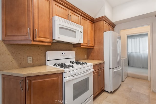 kitchen featuring decorative backsplash, light stone counters, white appliances, and light tile patterned floors