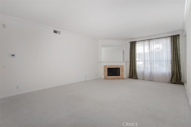 unfurnished living room featuring light colored carpet, crown molding, and a fireplace