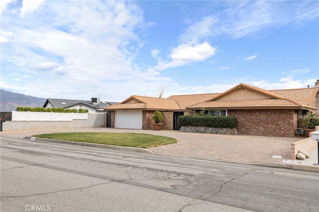 ranch-style house with a front yard, a mountain view, and a garage