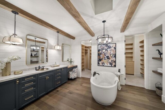 bathroom with a bathing tub, wood-type flooring, vanity, and beamed ceiling