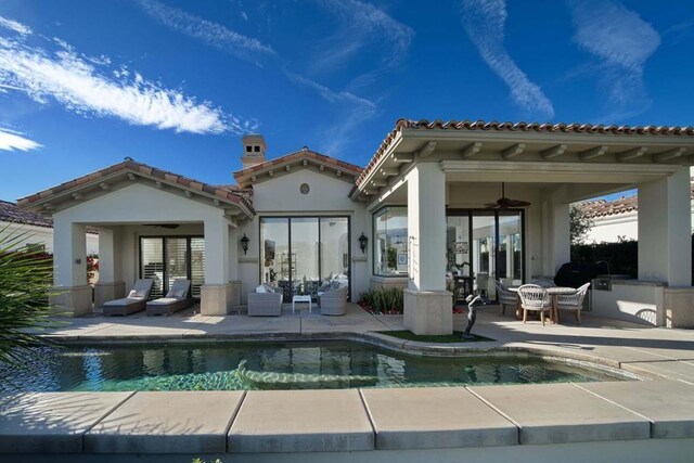 rear view of house with ceiling fan, an outdoor kitchen, and a patio