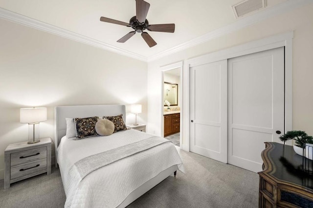 bedroom featuring ensuite bathroom, light colored carpet, ceiling fan, ornamental molding, and a closet