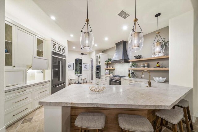 kitchen featuring premium range hood, pendant lighting, sink, a breakfast bar area, and stainless steel appliances