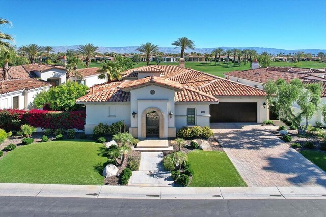 mediterranean / spanish home with a mountain view, a front lawn, and a garage