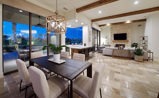 dining area featuring a chandelier, beam ceiling, and a fireplace