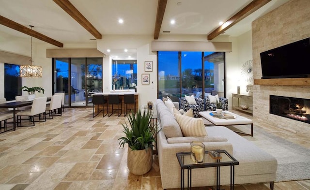 living room with a large fireplace, a notable chandelier, and beamed ceiling