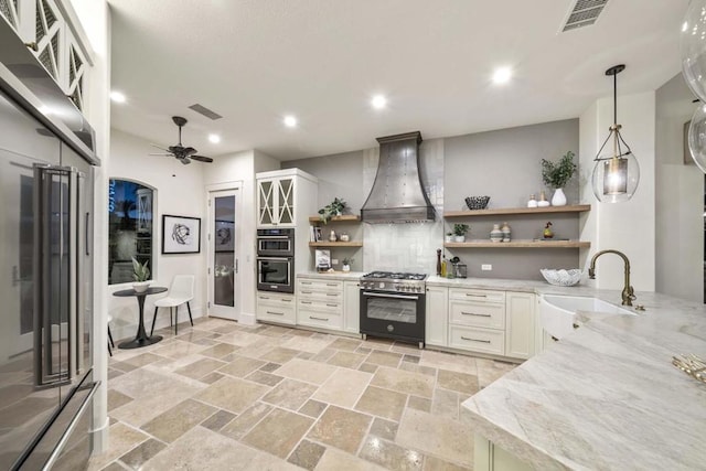 kitchen with range with gas cooktop, decorative light fixtures, premium range hood, sink, and white cabinetry