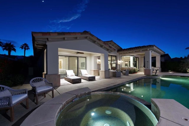 pool at twilight with an in ground hot tub, ceiling fan, and a patio