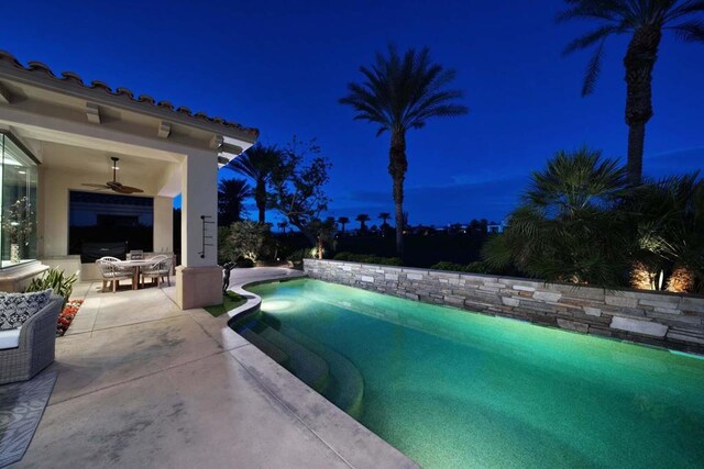 pool at twilight featuring ceiling fan and a patio