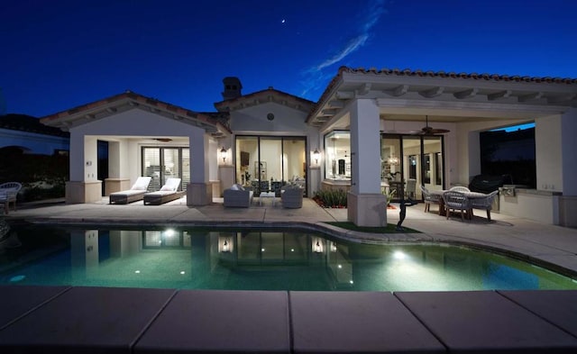 pool at twilight featuring ceiling fan, an outdoor kitchen, and a patio