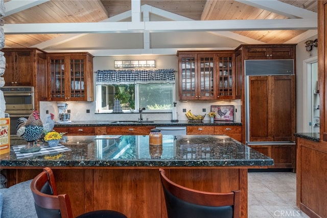 kitchen with sink, stainless steel appliances, dark stone counters, and light tile patterned flooring