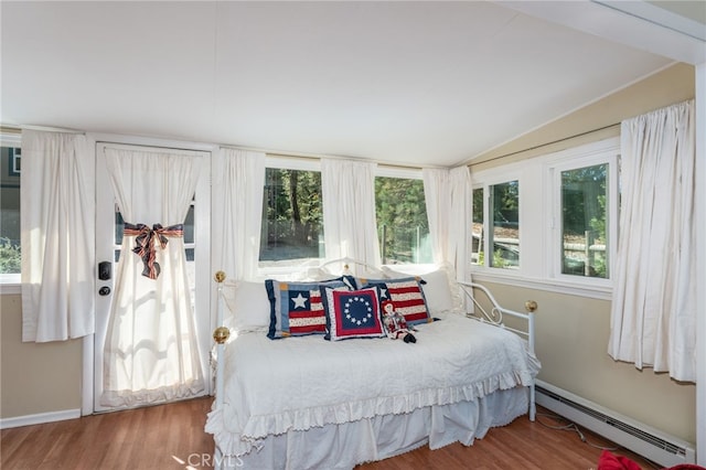 bedroom featuring lofted ceiling, a baseboard heating unit, and wood-type flooring