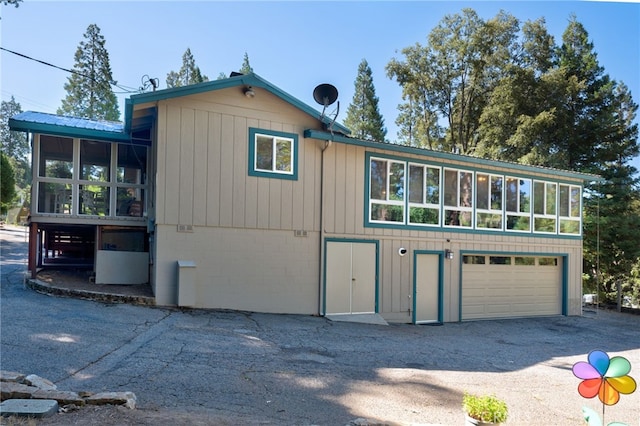 view of property exterior with a garage and a sunroom