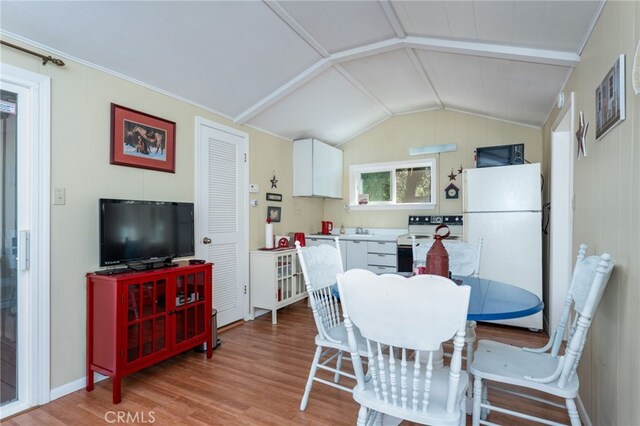 dining room with sink, light hardwood / wood-style flooring, and lofted ceiling