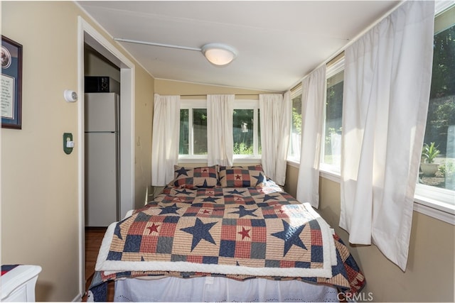 bedroom with vaulted ceiling and white refrigerator