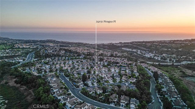 aerial view at dusk featuring a water view