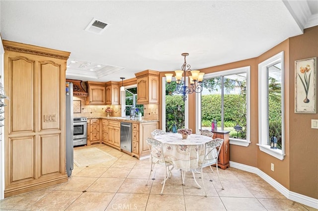 kitchen featuring pendant lighting, appliances with stainless steel finishes, backsplash, ornamental molding, and a chandelier